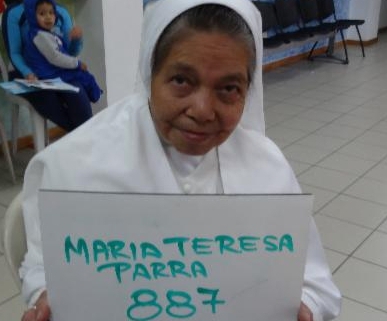 Older lady posing with a sign which says Maria Teresa Parra 887
